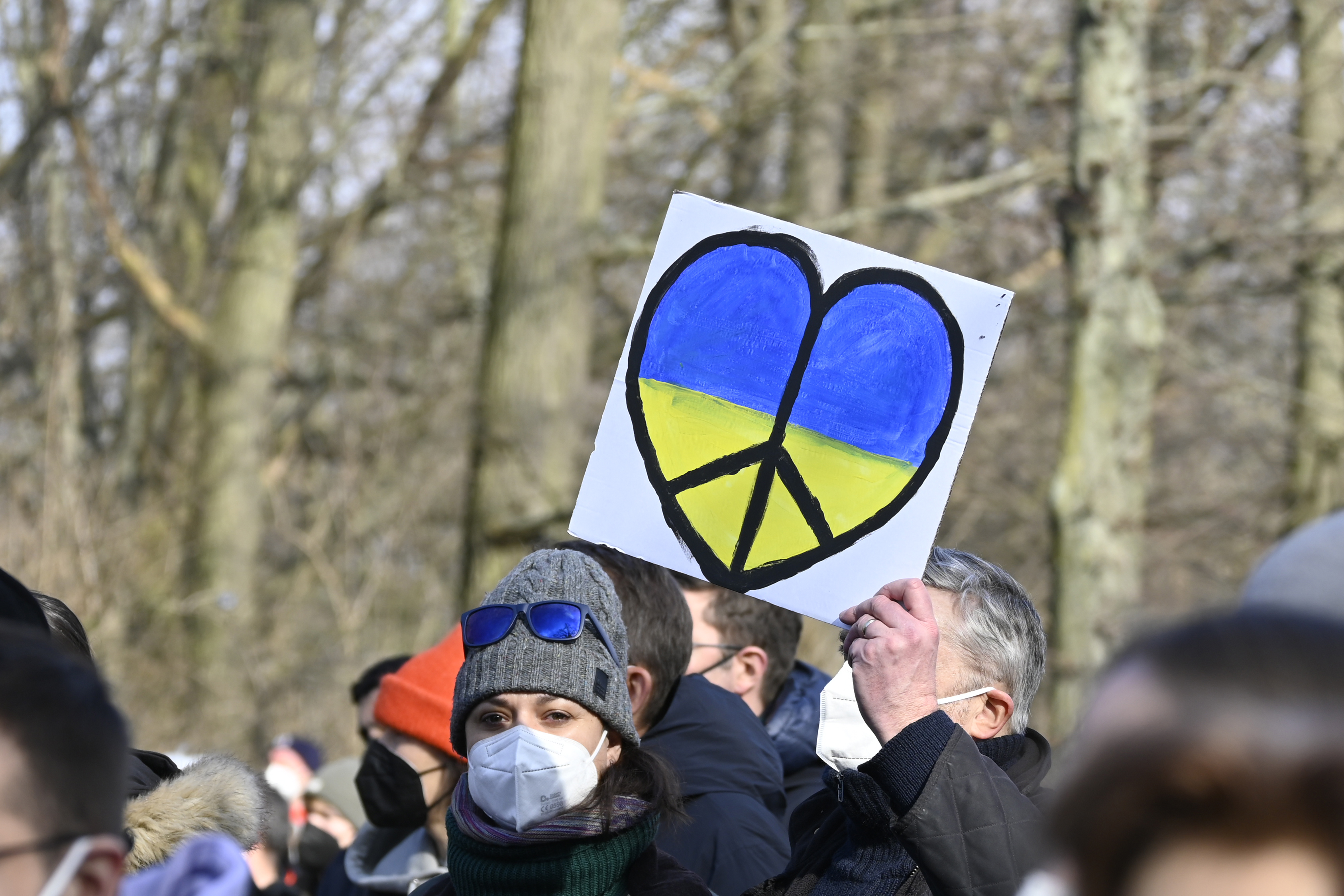 Demonstrierender in Berlin hält Schild hoch mit einem Herz in den Farben der ukrainischen Flagge.