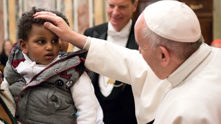 Papst Franziskus und ein junger Migrant.